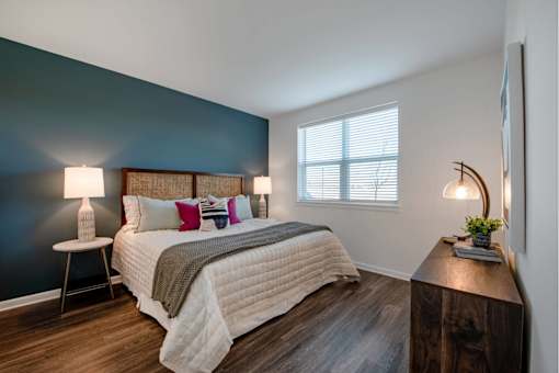 Spacious bedroom with bright windows and plank flooring