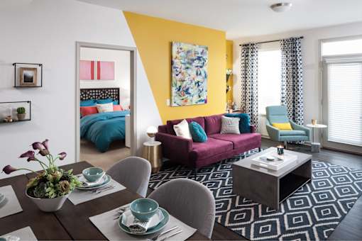 A modern living room with a dining table set for two.