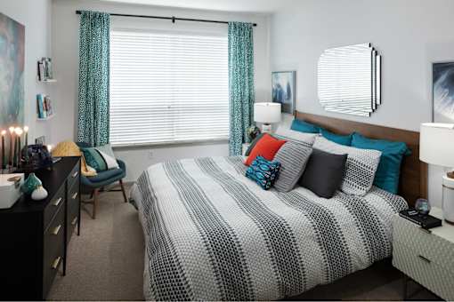 A bedroom with a bed, chair, and a nightstand.