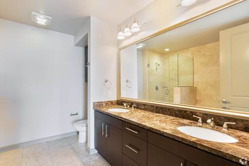 A bathroom with a marble countertop and a large mirror.