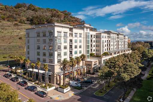 A large white hotel with a parking lot in front.