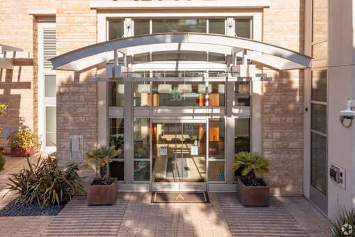 The entrance to a building with a glass door and a stone wall.