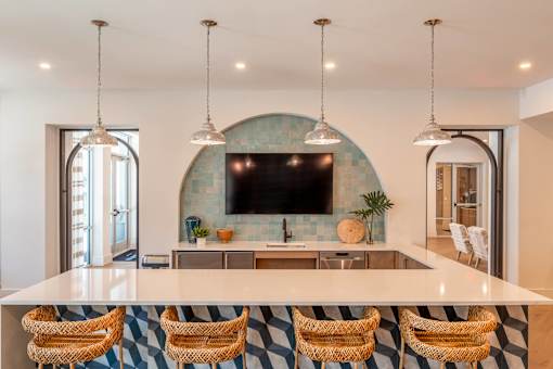 A kitchen with a bar area and a television mounted on the wall.