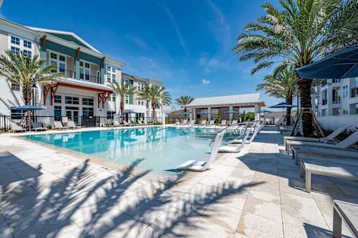 A large swimming pool surrounded by palm trees and lounge chairs.