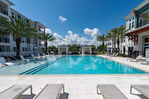 A swimming pool surrounded by lounge chairs and palm trees.