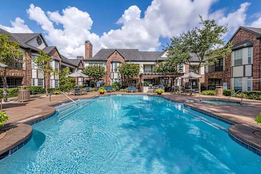 Large outdoor pool surrounded by trees at Joule on Memorial apartments in Harris County, TX.
