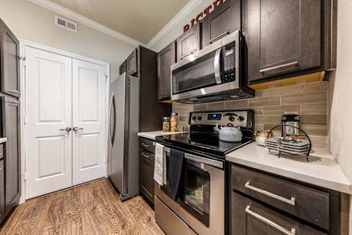 A kitchen with a black stove top oven and microwave above it.