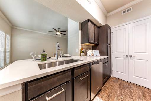 A kitchen with a white counter top and wooden floors.