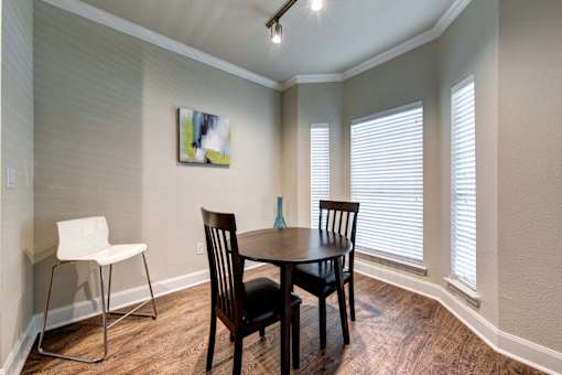 A dining room with a table, chairs and a painting on the wall.