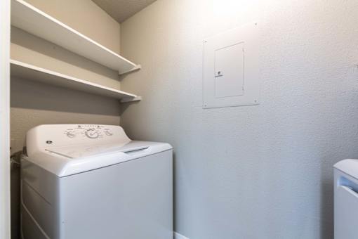 A white washing machine sits in a laundry room.