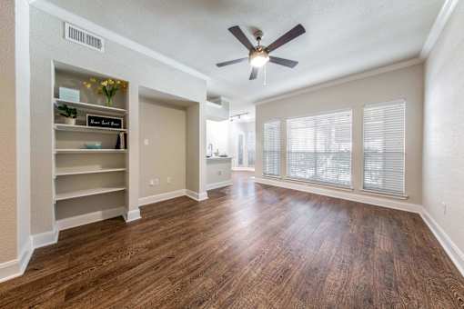 A room with a ceiling fan and wooden flooring.