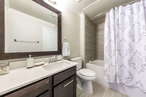 A bathroom with a white toilet, sink, and shower curtain.
