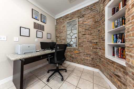 A room with a brick wall and a desk with a printer on it.