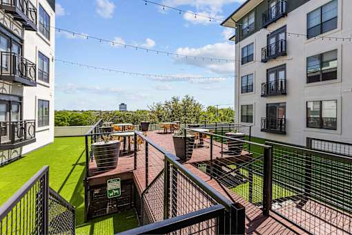 A patio area with a table and chairs is surrounded by a metal fence.