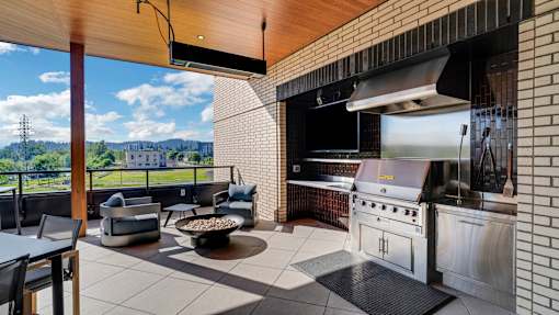 A modern outdoor kitchen with a grill and seating area.