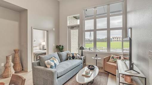 A living room with a grey couch and a large window.