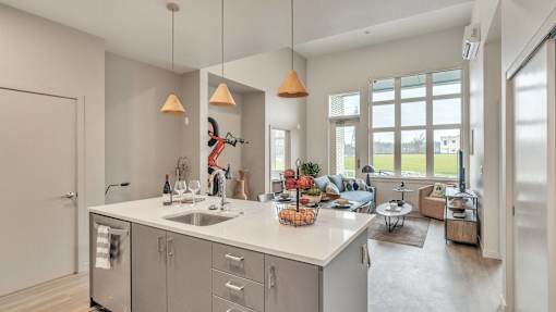 A kitchen with a sink, a refrigerator, and a counter with a basket of fruit on it.