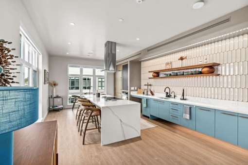 A modern kitchen with a white island and blue cabinets.