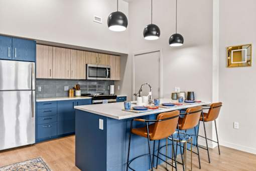 A kitchen with a blue island and chairs.