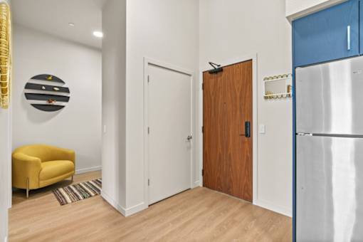 A yellow chair sits in a room with a white door and a wooden door.