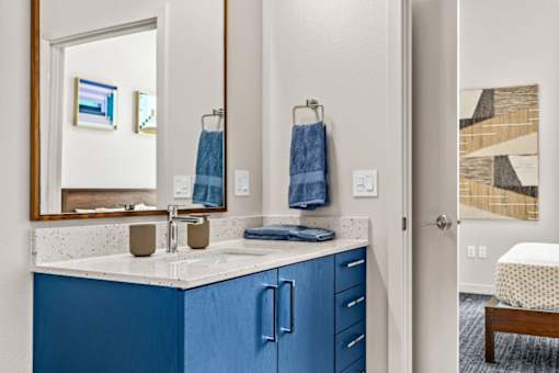 A bathroom with blue cabinets and a white countertop.