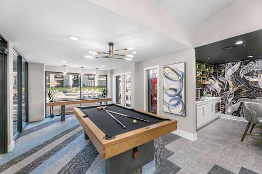 A pool table is in the middle of a room with a ceiling fan and a chair.