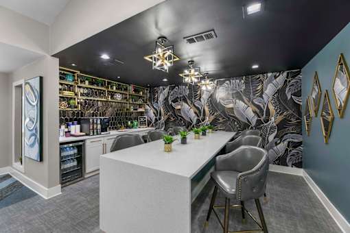 A modern kitchen with a white counter and grey chairs.