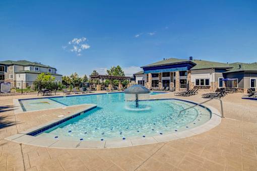 A large outdoor swimming pool with a fountain in the middle.
