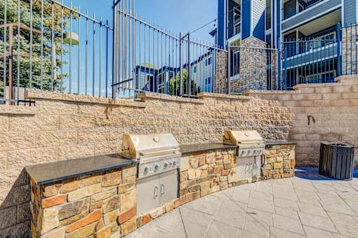 A stone wall with a built-in grill and a metal fence.