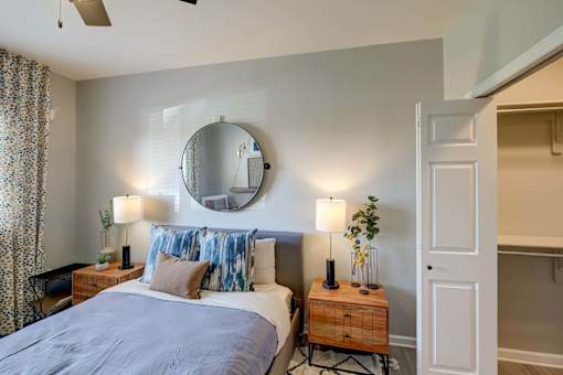 A bedroom with a bed, nightstands, and a round mirror on the wall.