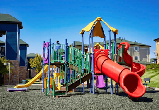 A playground with a red slide and a yellow canopy.