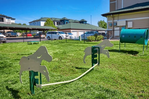 A playground with a horse-shaped swing set in the foreground.