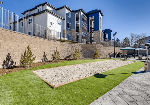 A modern building with a blue and white exterior is surrounded by a well-maintained lawn and a stone wall.