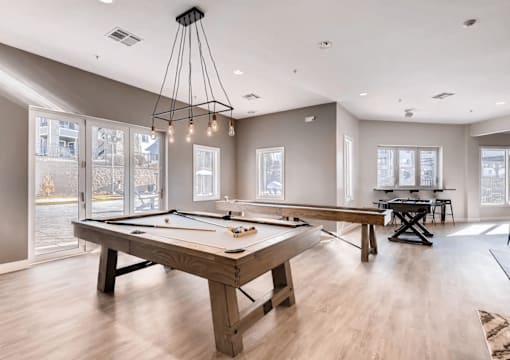 A billiard table is in the middle of a room with a pool table and a foosball table.