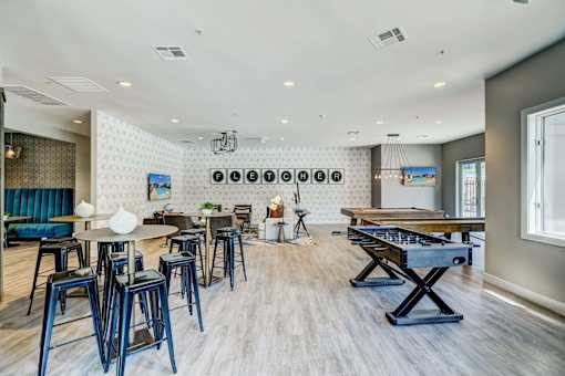 A room with a pool table and bar stools.