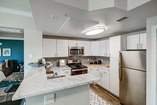 A kitchen with a marble countertop and stainless steel appliances.