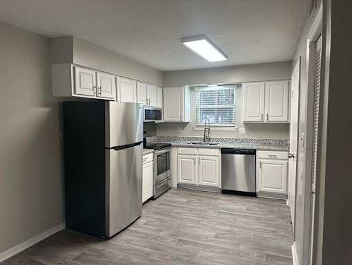 A kitchen with a black refrigerator and white cabinets.