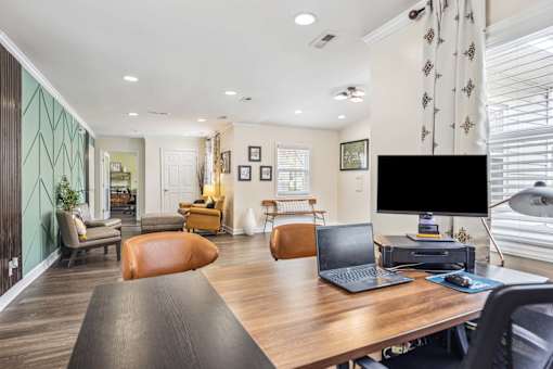 A modern home office with a laptop and a desktop computer on a wooden desk.