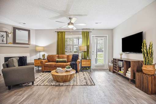 A living room with a grey couch, a brown sofa, a wooden coffee table, a flat screen TV, and a ceiling fan.