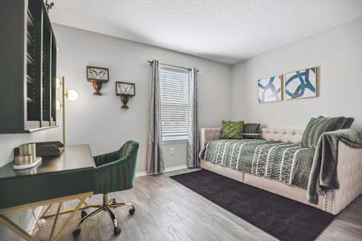 A bedroom with a bed, chair, and desk.