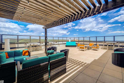 A patio with a wooden roof and several chairs and tables.