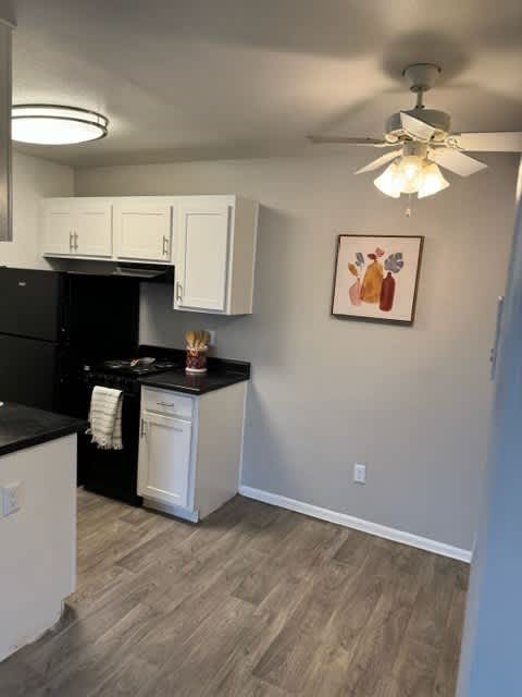 A kitchen with black appliances and white cabinets.