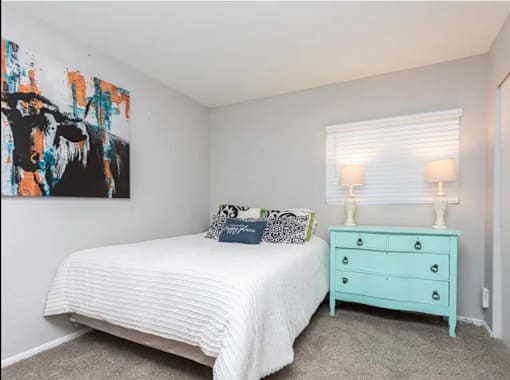 A bedroom with a white bed and a blue dresser.
