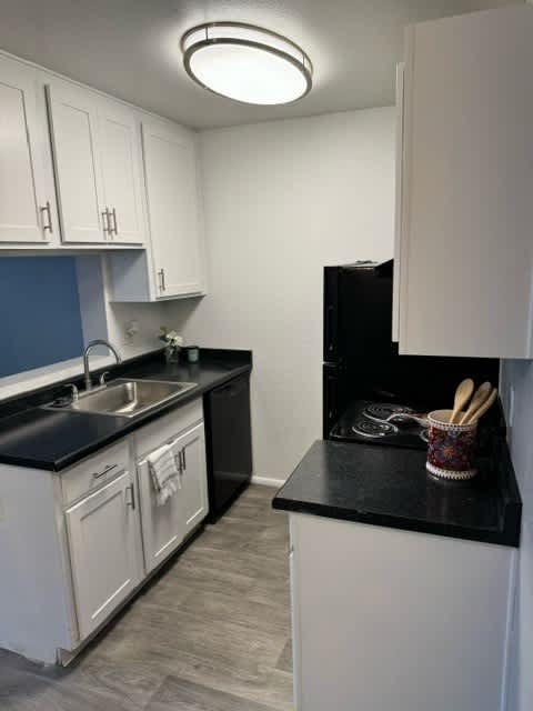 A kitchen with black countertops and white cabinets.