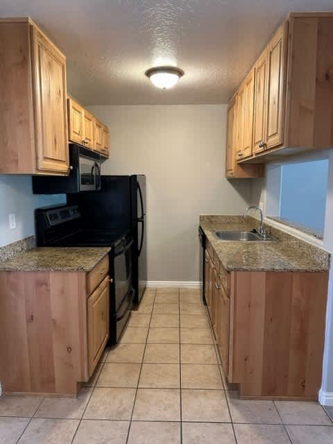 A kitchen with black appliances and wooden cabinets.