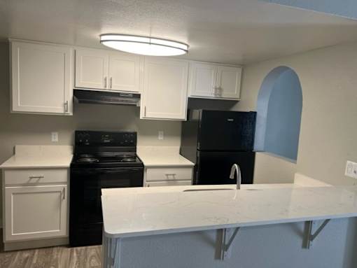 A kitchen with black appliances and white cabinets.