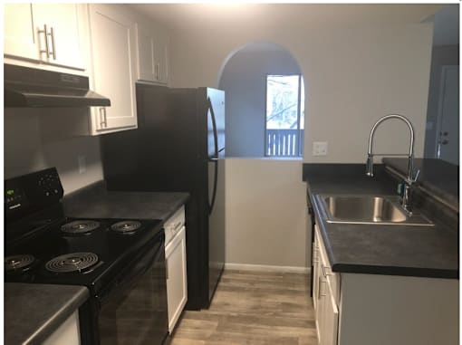 A kitchen with black countertops and white cabinets.