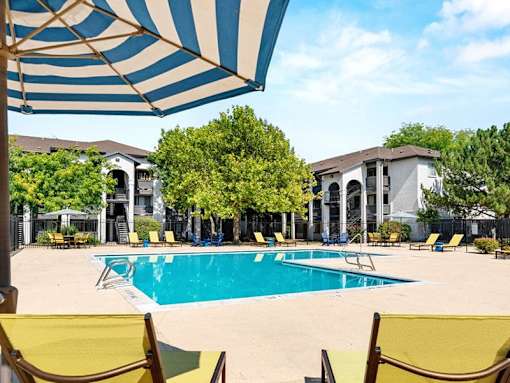 A pool surrounded by yellow chairs and umbrellas.
