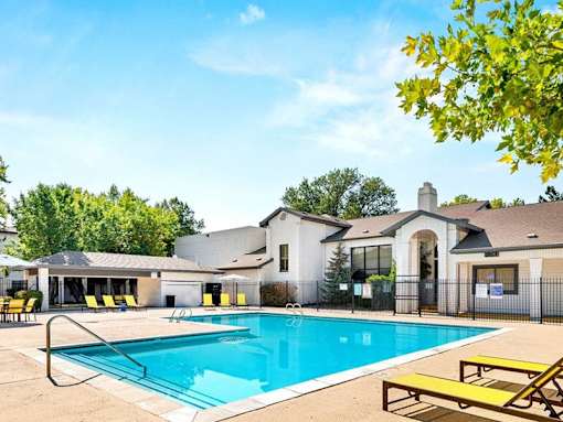 A pool with a yellow bench and a building in the background.