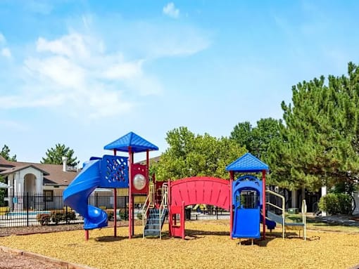 A playground with a blue slide, red slide, and a blue and red play structure.